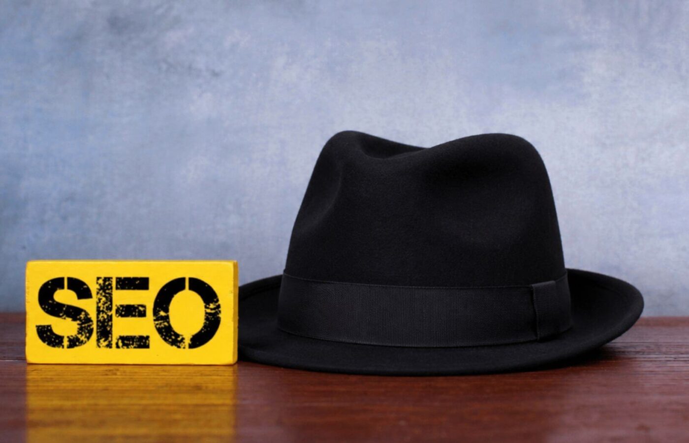 Yellow SEO sign beside a black hat on a wooden surface
