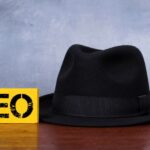 Yellow SEO sign beside a black hat on a wooden surface