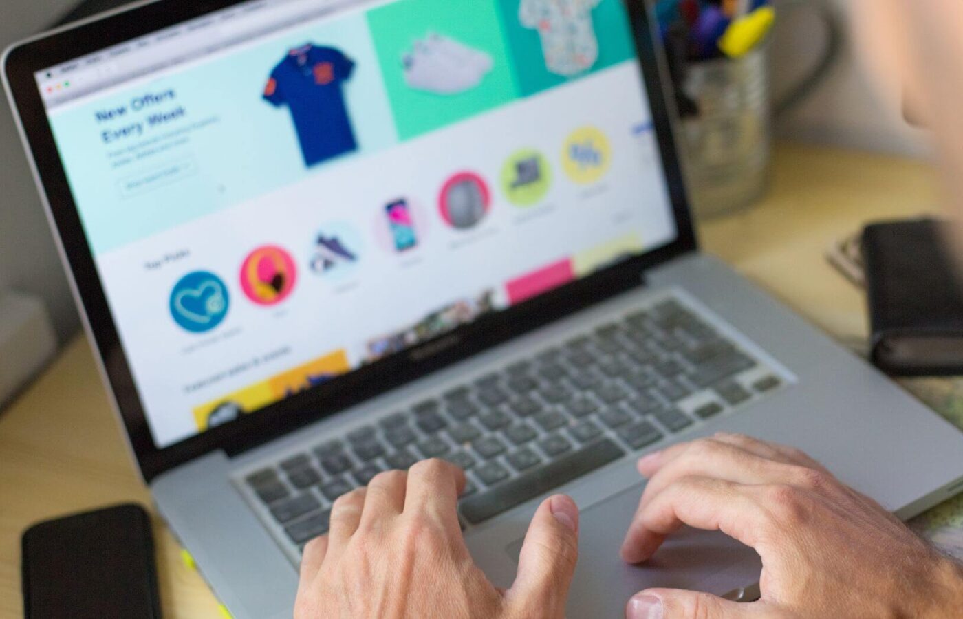 Person using a laptop to browse an online shop with clothing and product listings
