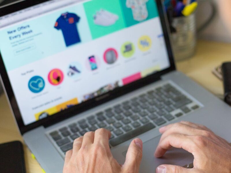 Person using a laptop to browse an online shop with clothing and product listings